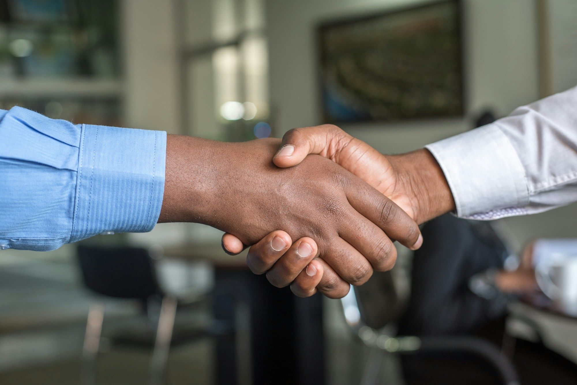 Two people shaking hands across a desk at a consultation