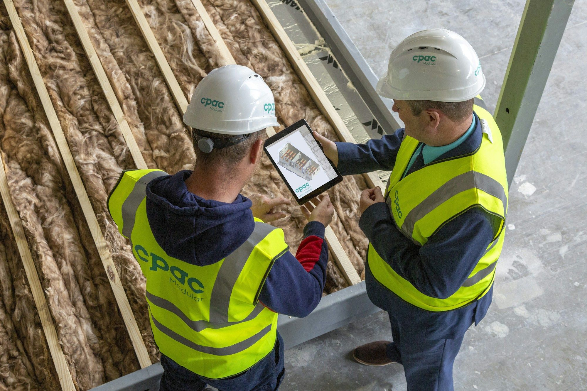 Two construction workers checking site plans on a tablet